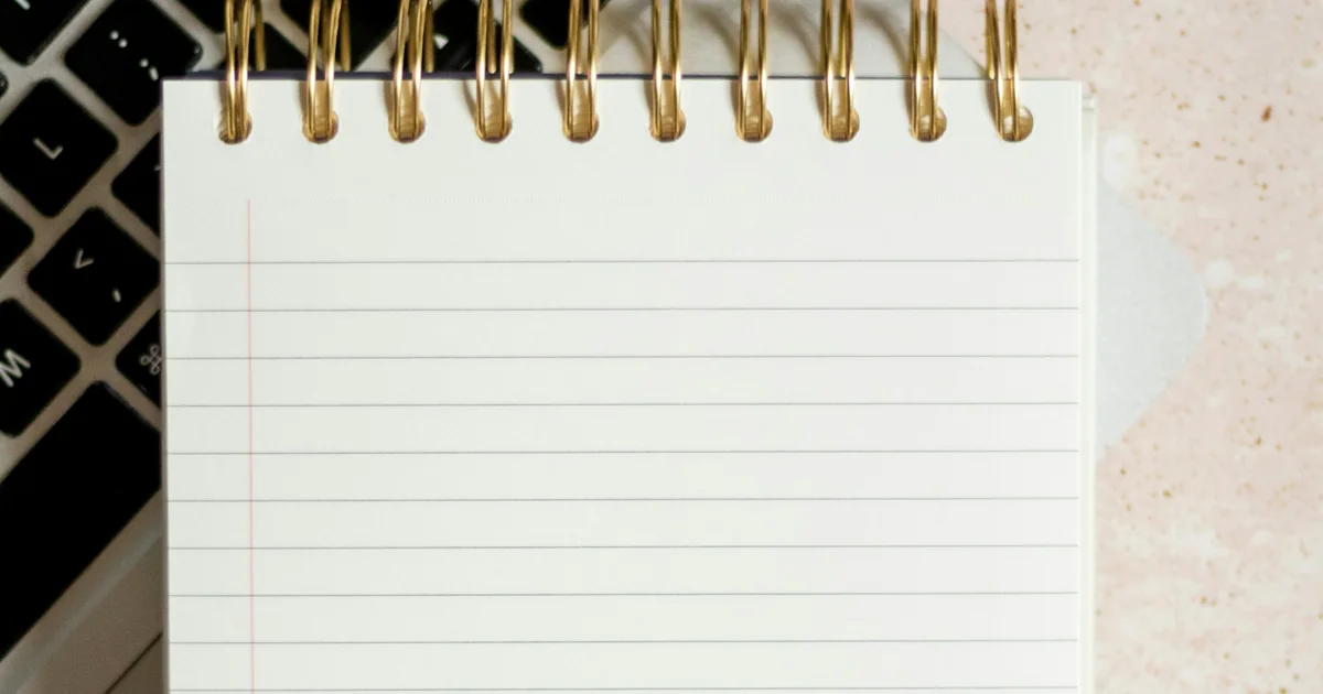 Bloc-notes blanc posé sur un ordinateur portable, vu du dessus