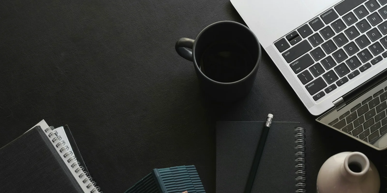 Poste d'étude sombre avec ordinateur portable, carnet et tasse